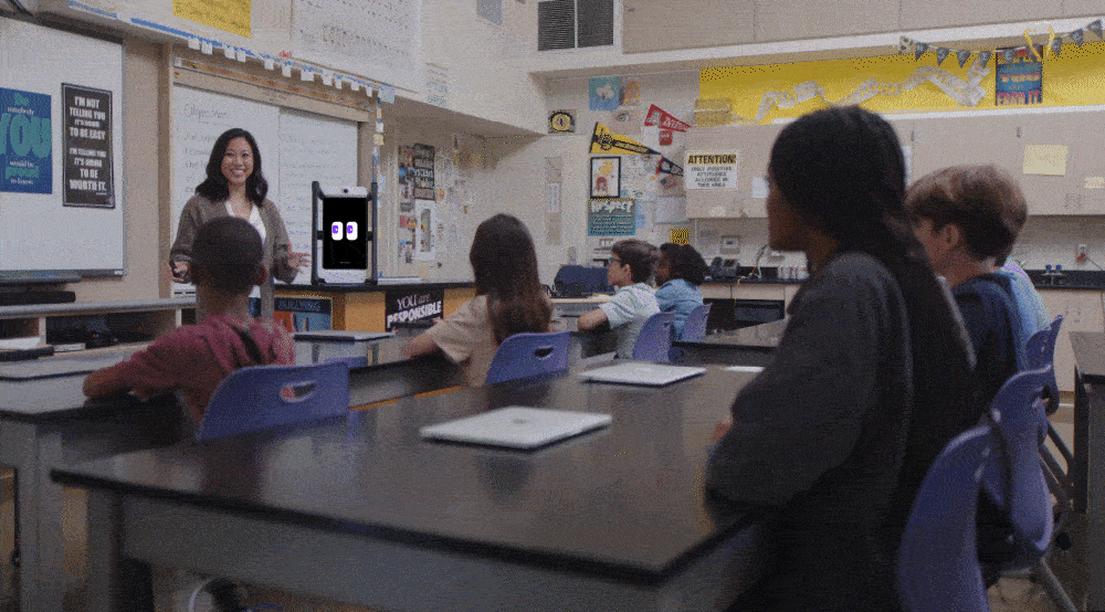 Animated sequence showing M2 co-teaching with the instructor at the desk, then guiding a small group of students.